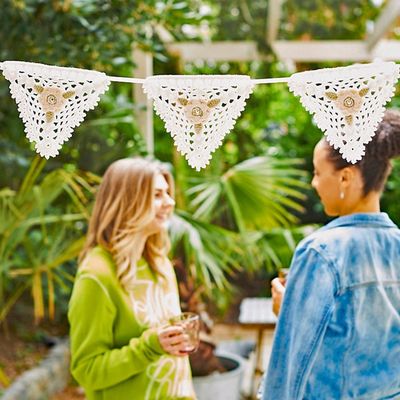 Cream crocheted bunting hanging in a garden.