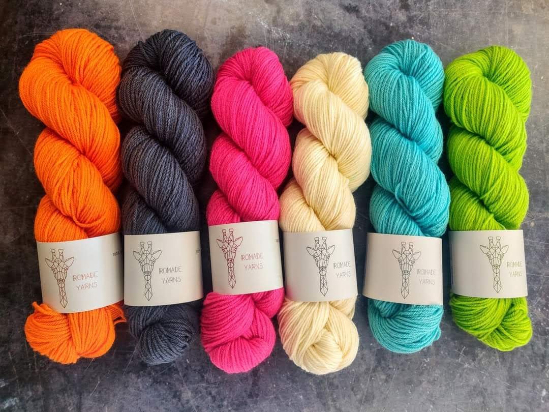 6 skeins of brightly coloured yarn on a dark grey background.