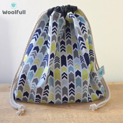 A drawstring bag in a white fabric with blue and green chevrons.