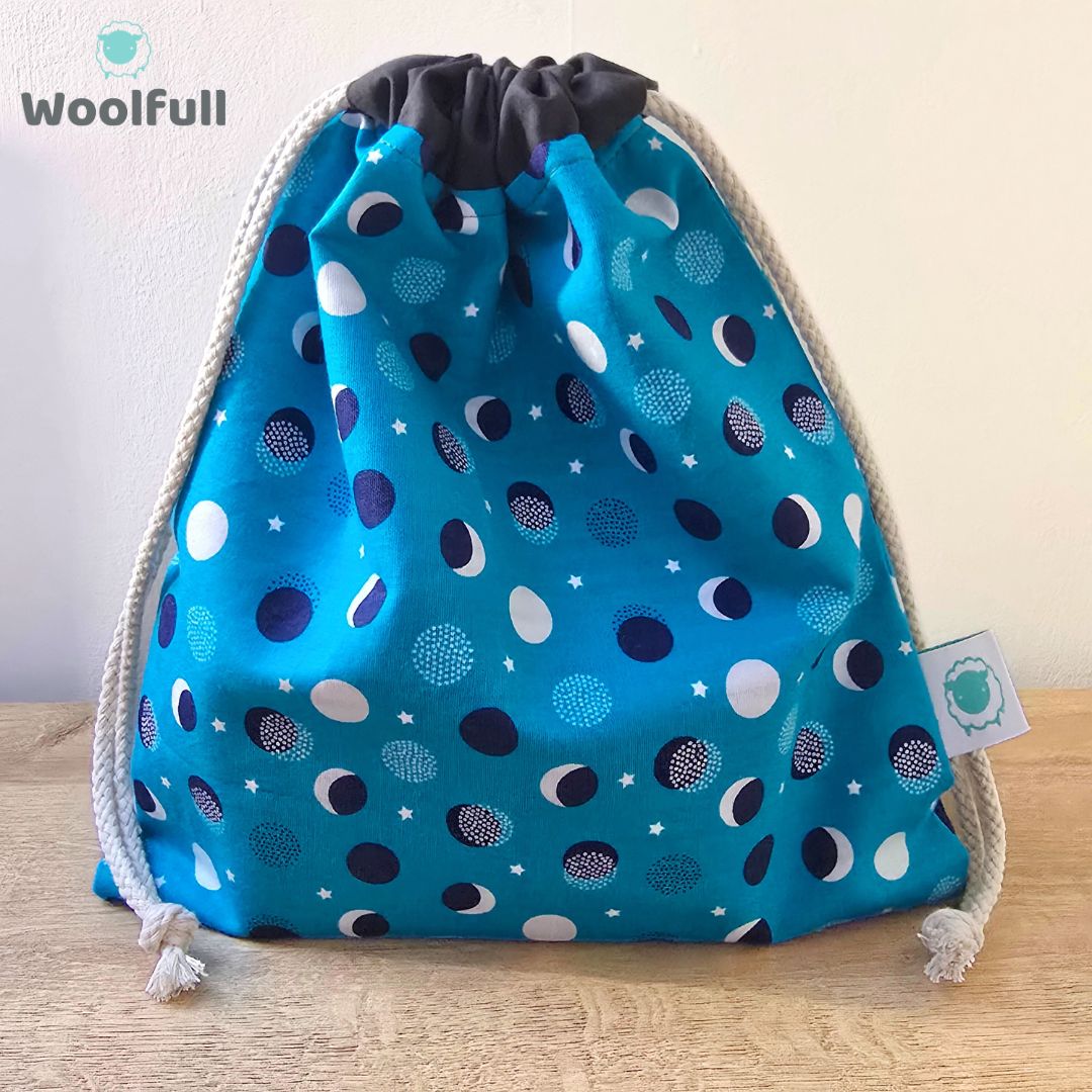 A drawstring bag in a blue fabric with navy and white spots.