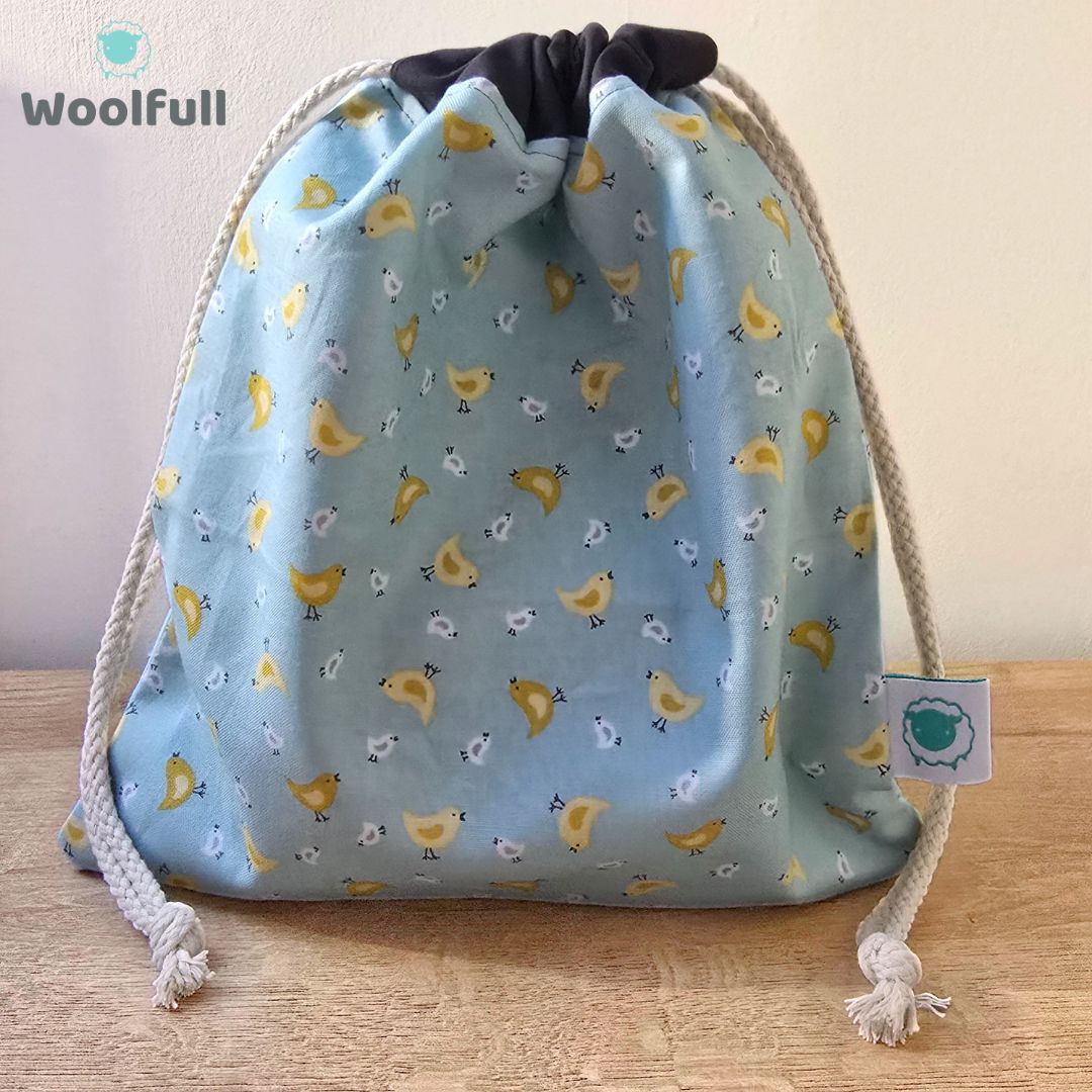 A drawstring bag in a blue fabric with yellow and white chicks.