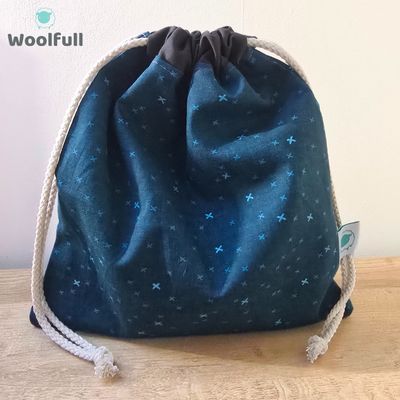 A drawstring bag in a dark blue fabric with light blue crosses.