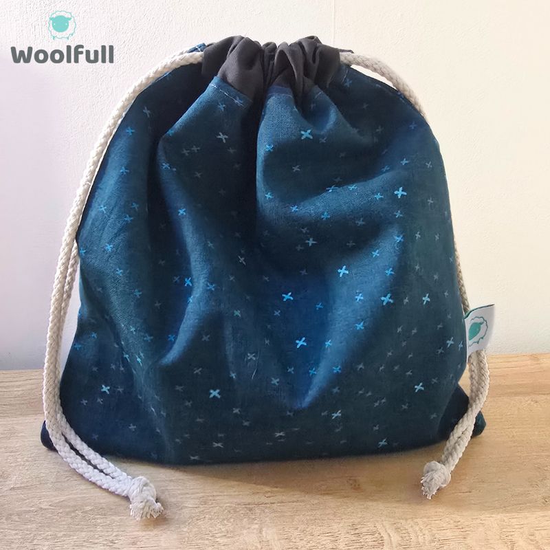 A drawstring bag in a dark blue fabric with light blue crosses.