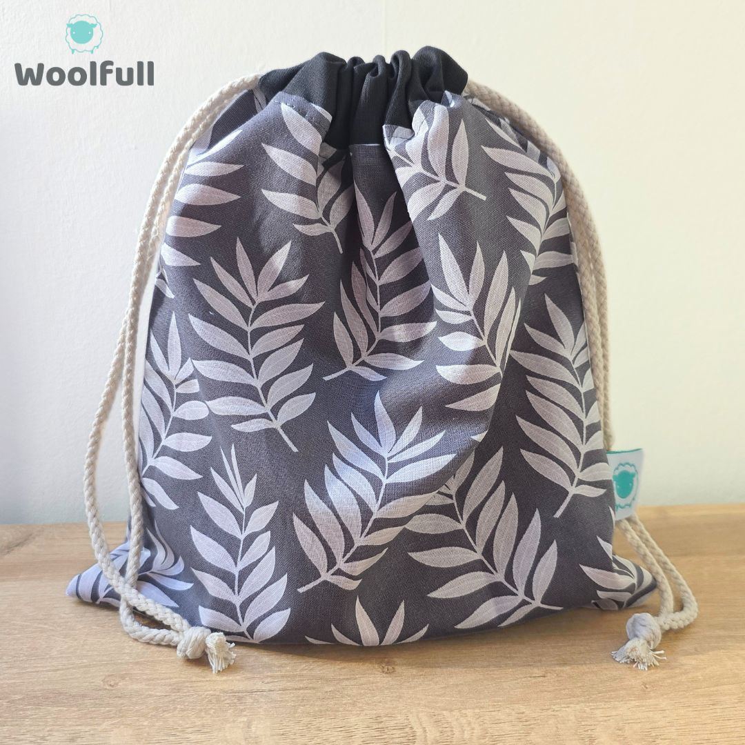 A drawstring bag in a grey fabric with white leaves.