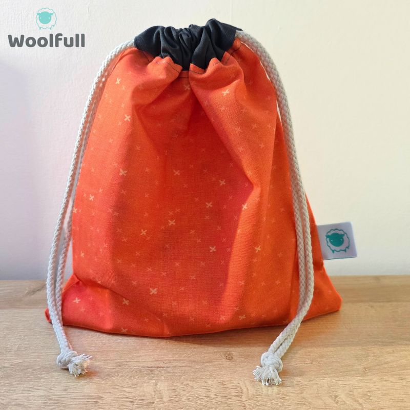 A drawstring bag in an orange fabric with small crosses.