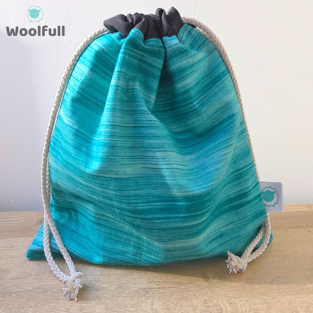 A drawstring bag in a teal striped fabric.