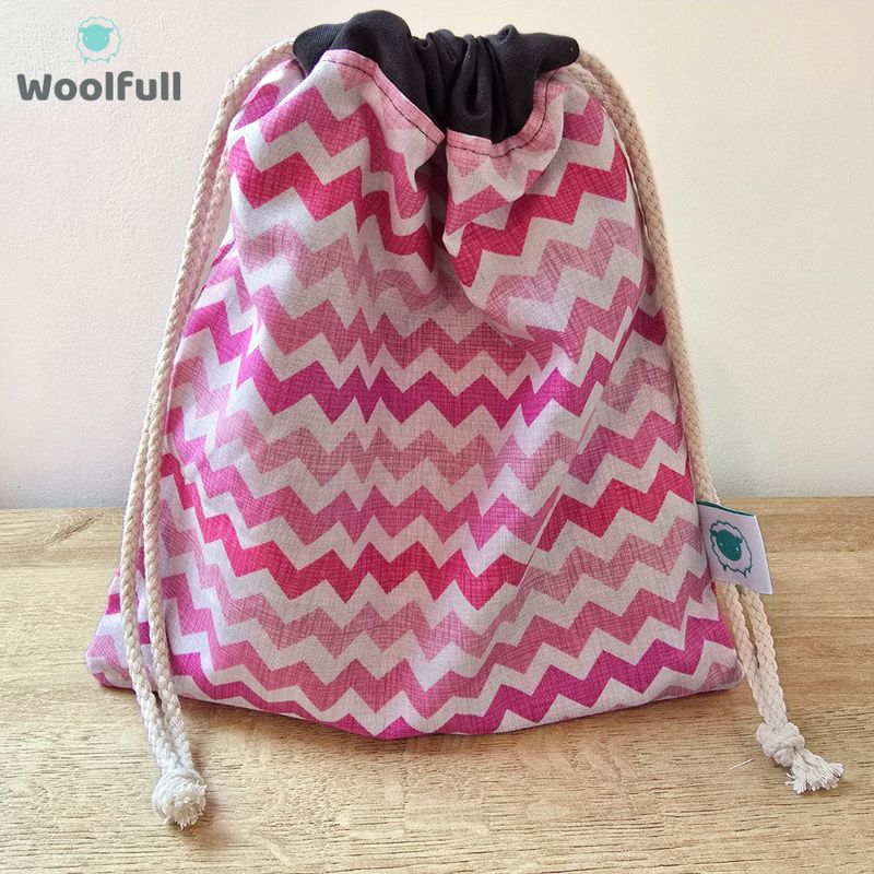 A drawstring bag in a white and pink zig zag fabric.