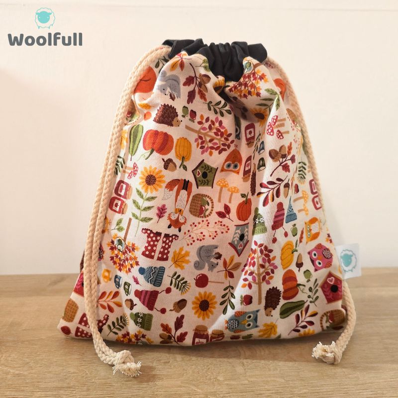 A drawstring bag in a white fabric with woodland images.