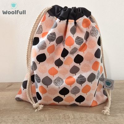 A drawstring bag in a white fabric with coral and grey trees.