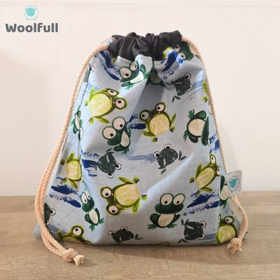 A drawstring bag in a blue fabric with green frogs.