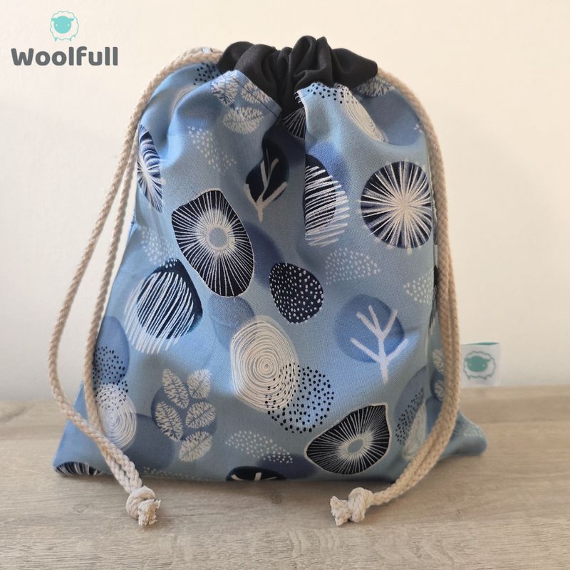 A drawstring bag in a light blue fabric with navy and white shapes.