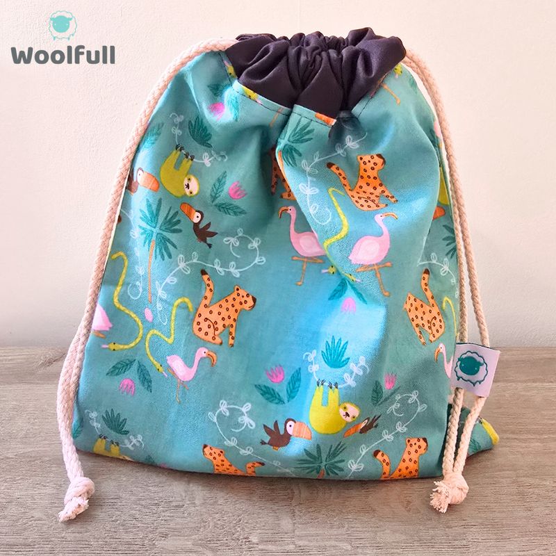 A drawstring bag in a teal fabric with jungle animals.