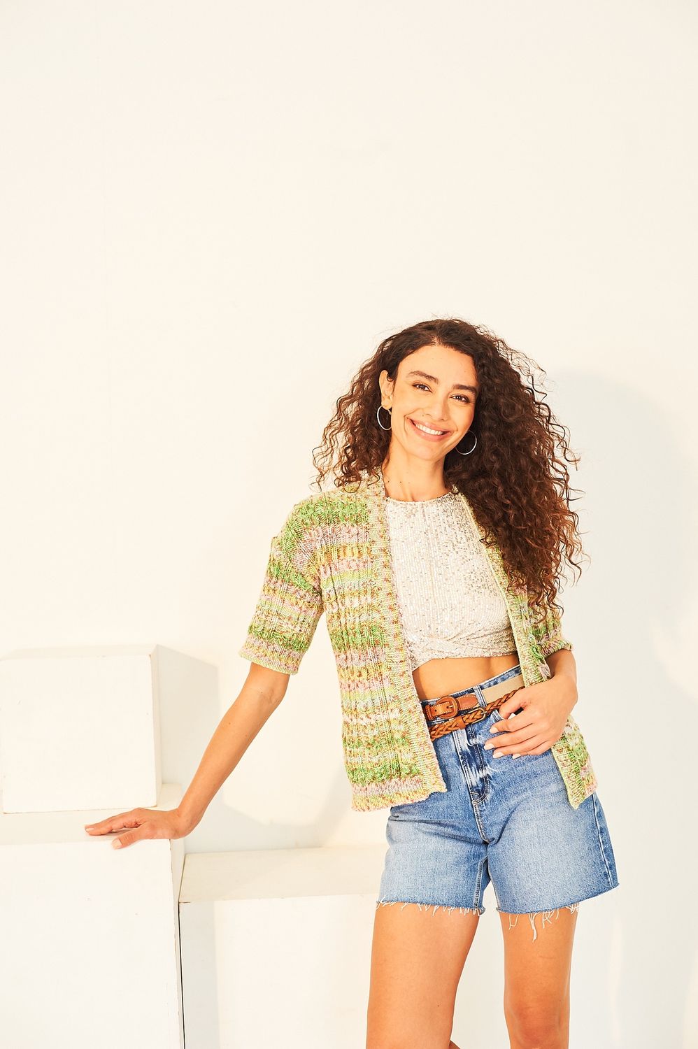 A woman is wearing a variegated yellow and green knitted cardigan.