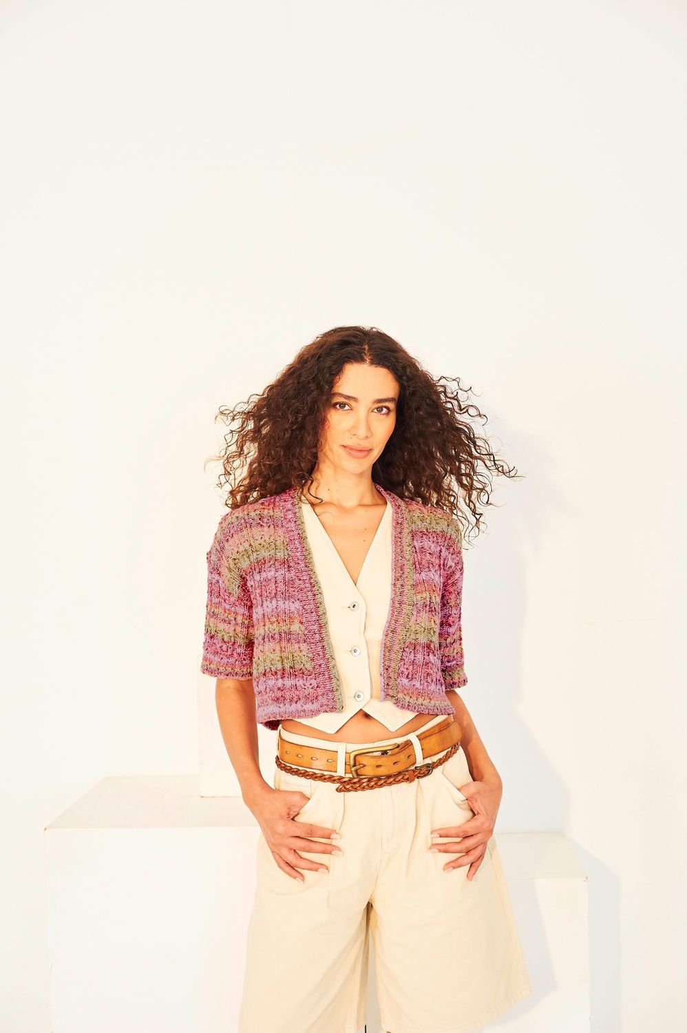 A woman is wearing a variegated pink and green knitted cardigan.