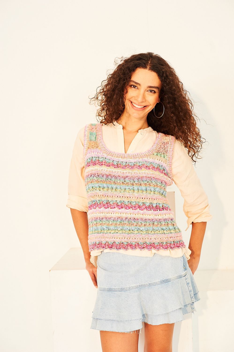 A woman is wearing a variegated pink and yellow knitted tank top.