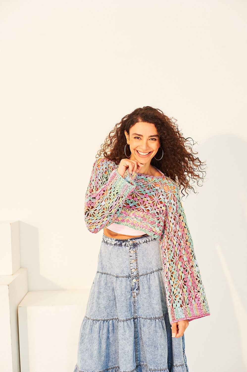 A woman is wearing a variegated blue and pink crocheted shrug.