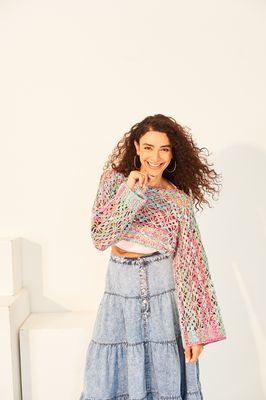 A woman is wearing a variegated blue and pink crocheted shrug.