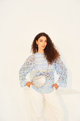 A woman is wearing a variegated green and blue crocheted top.