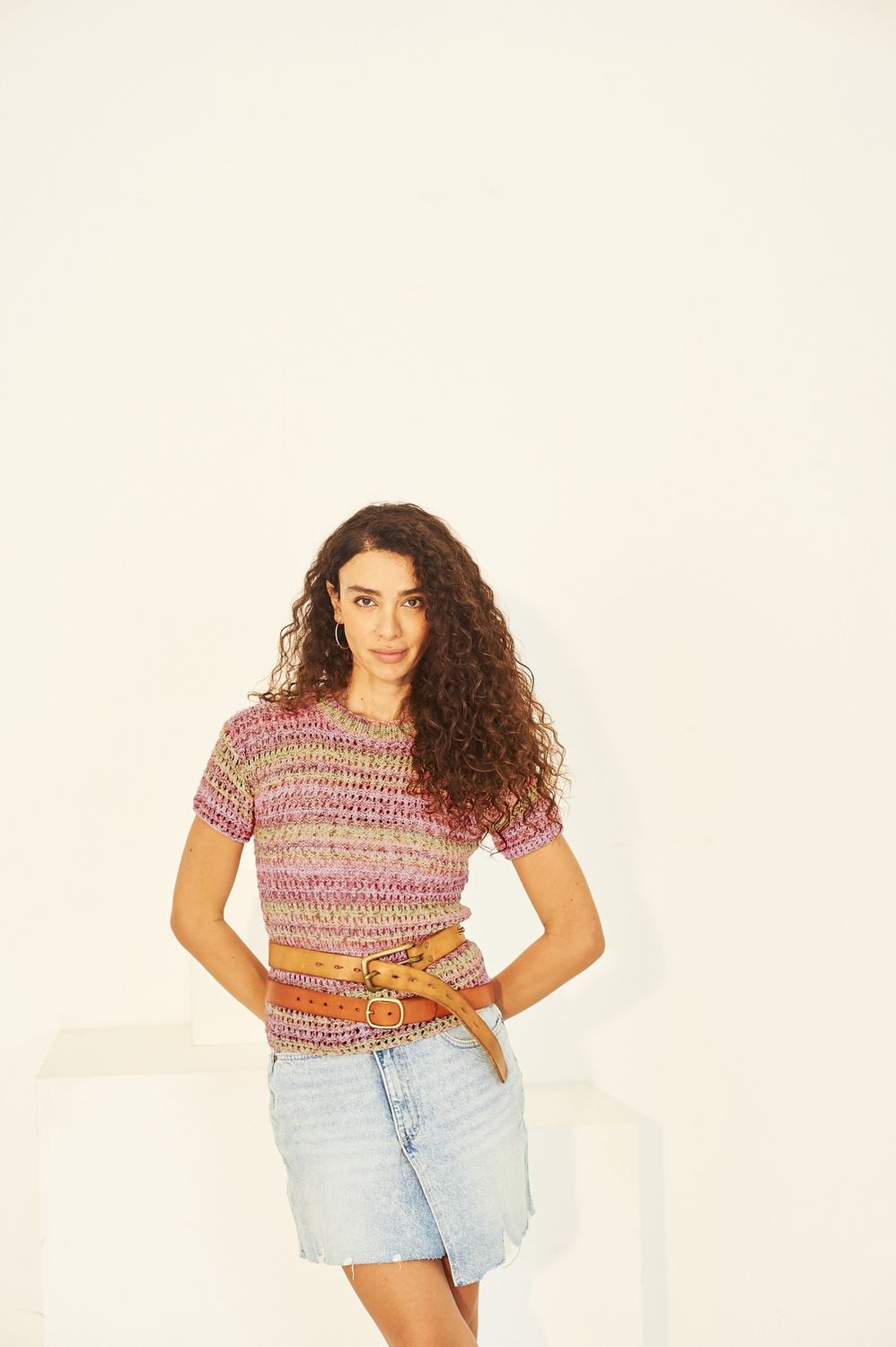 A woman is wearing a variegated green and pink knitted sweater.