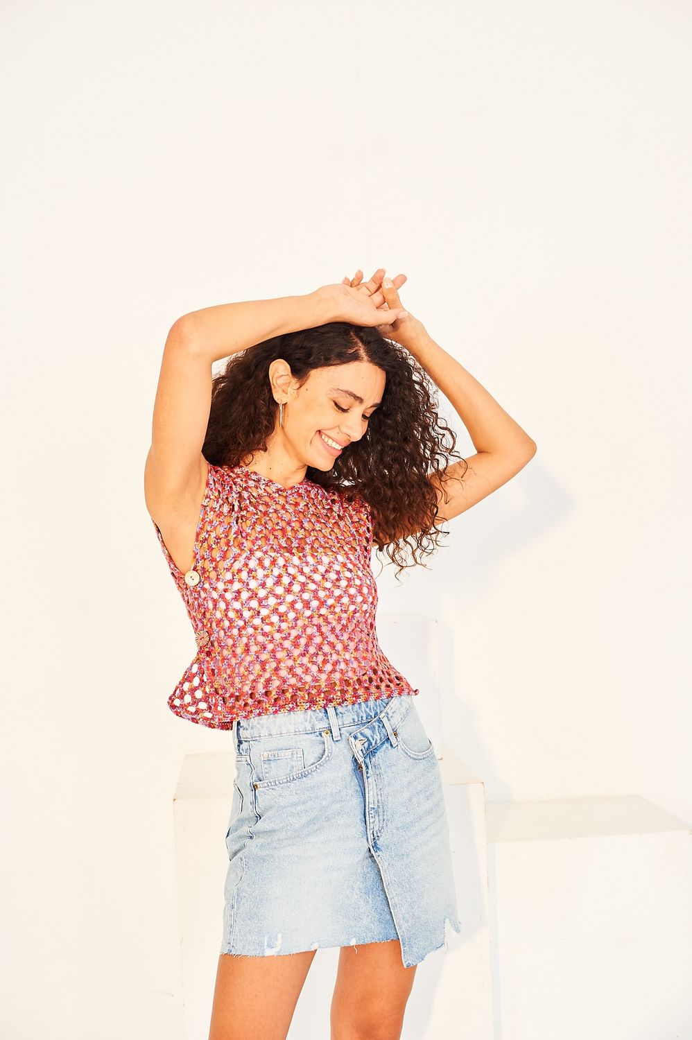 A woman is wearing a variegated red and blue crocheted tank top.