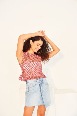 A woman is wearing a variegated red and blue crocheted tank top.