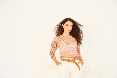 A woman is wearing a variegated green and pink crocheted sweater.
