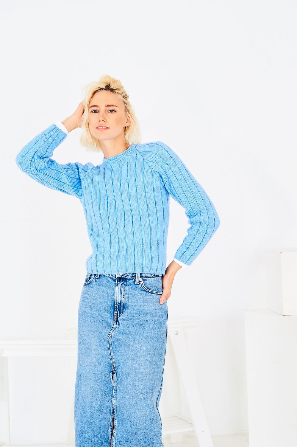 A woman is wearing a pale blue knitted sweater.
