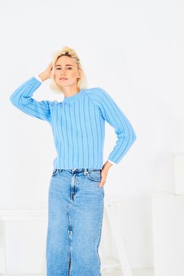 A woman is wearing a pale blue knitted sweater.