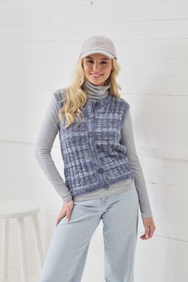 A woman is wearing a knitted waistcoat in a variegated blue and grey yarn.