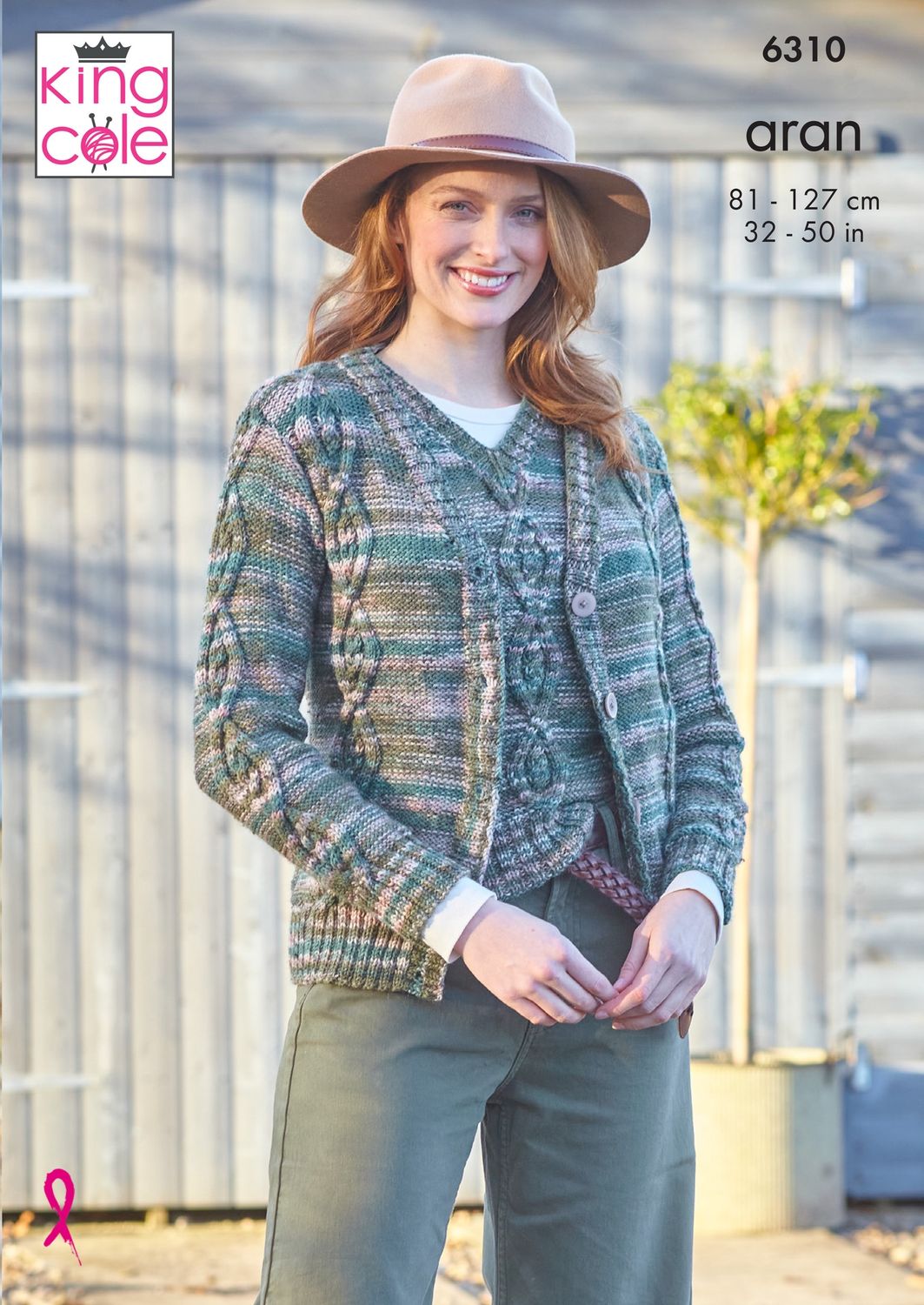 A woman is wearing a cable knit cardigan in a variegated green and brown yarn.