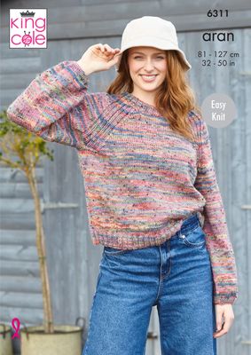 A woman is wearing a knitted sweater in a variegated pink, blue and green yarn.