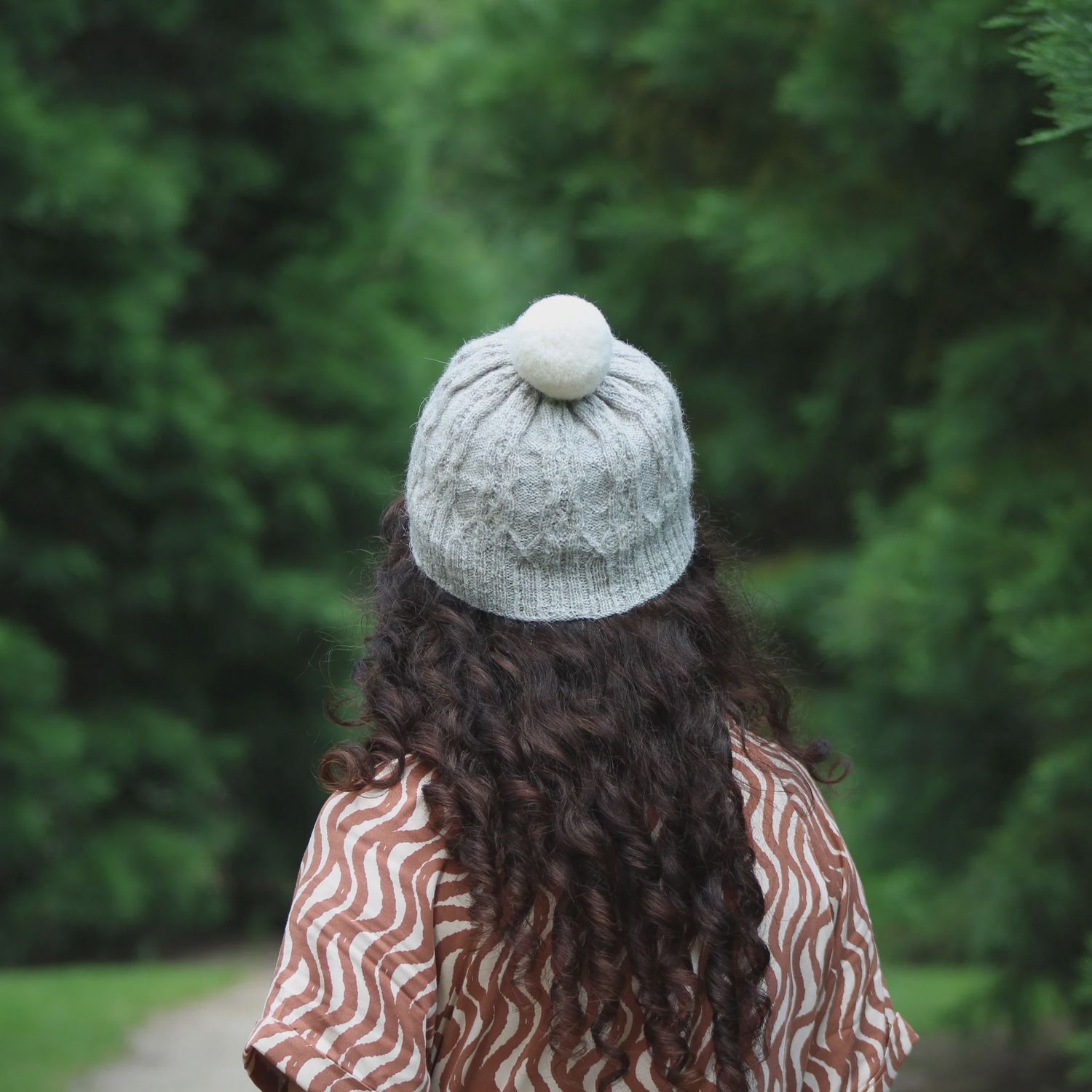 A woman is wearing a cream knitted hat with cream pompom.