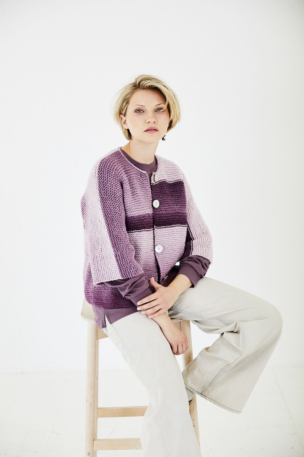 A woman is wearing a variegated purple knitted cardigan.