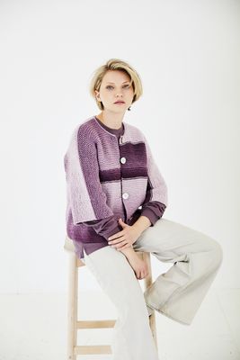 A woman is wearing a variegated purple knitted cardigan.