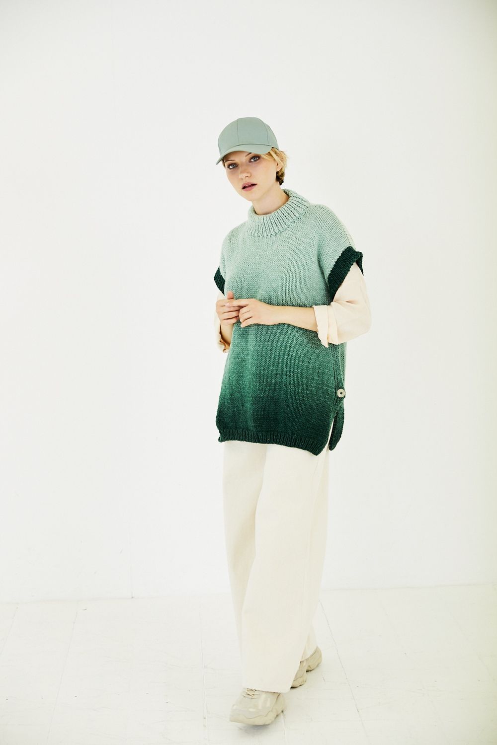 A woman is wearing a knitted tank top in a green gradient yarn.