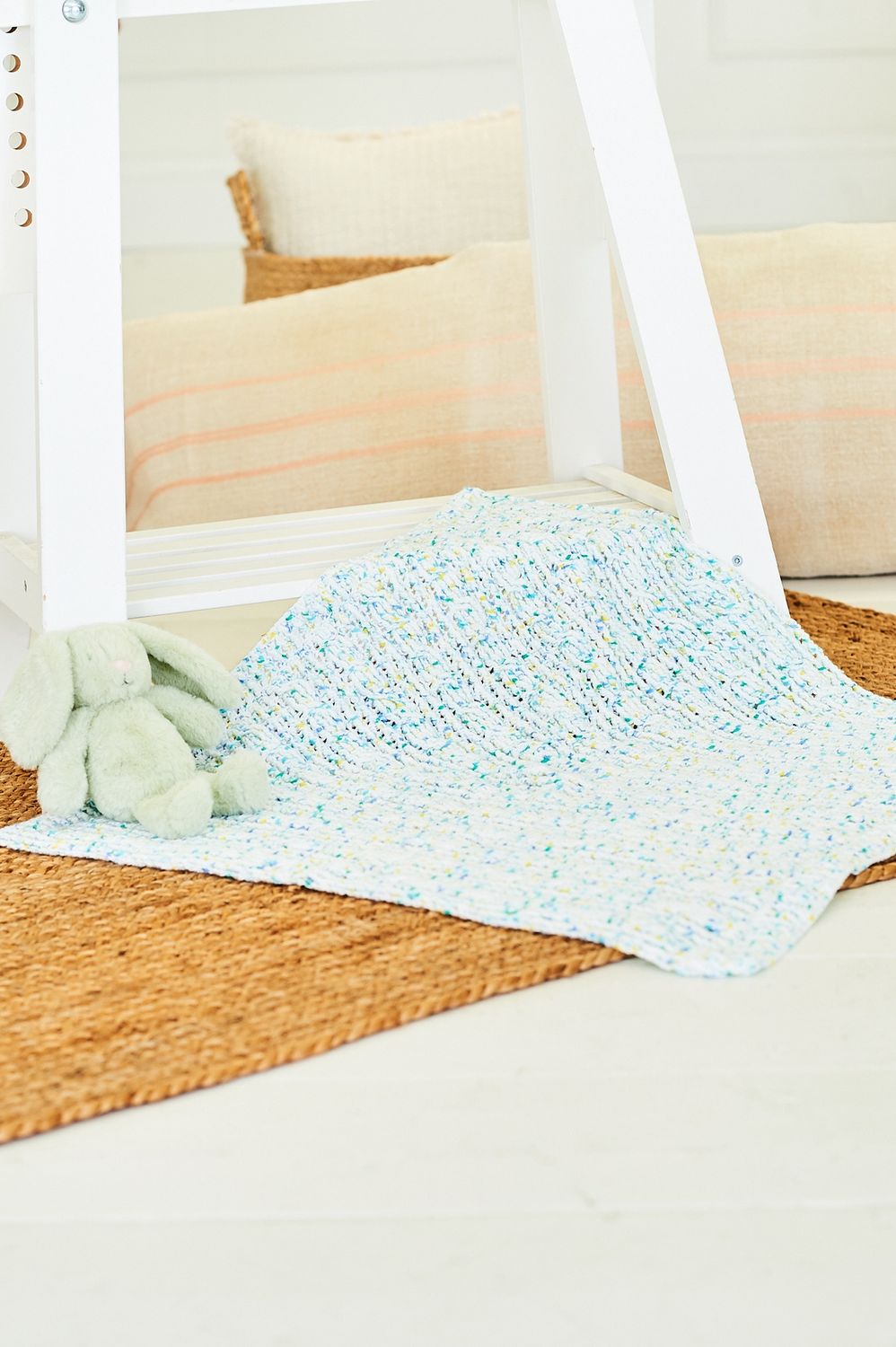 A crocheted blanket in a white yarn with small blue flecks.
