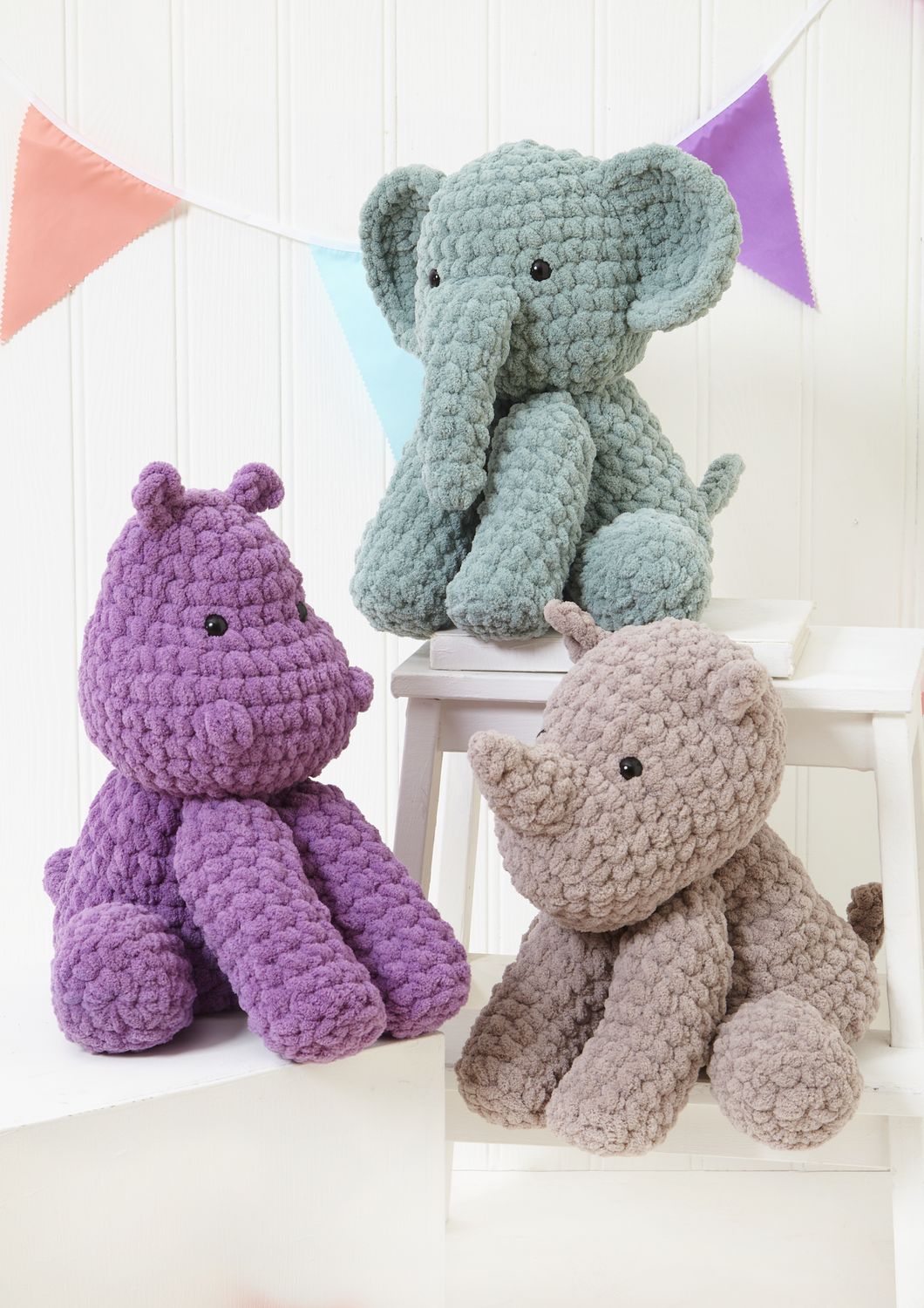 3 crocheted toys, a duck egg blue elephant, a purple hippo and a grey rhino.