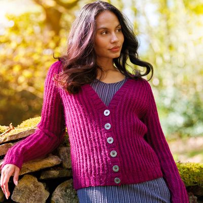 A woman is wearing a dark red knitted cardigan.