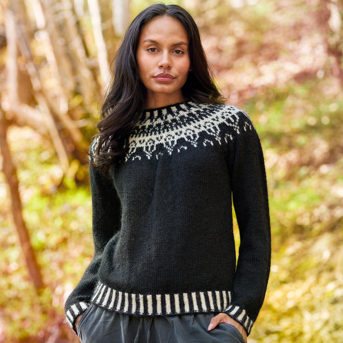 A woman is wearing a black knitted sweater with cream  colourwork around the yoke and rib.