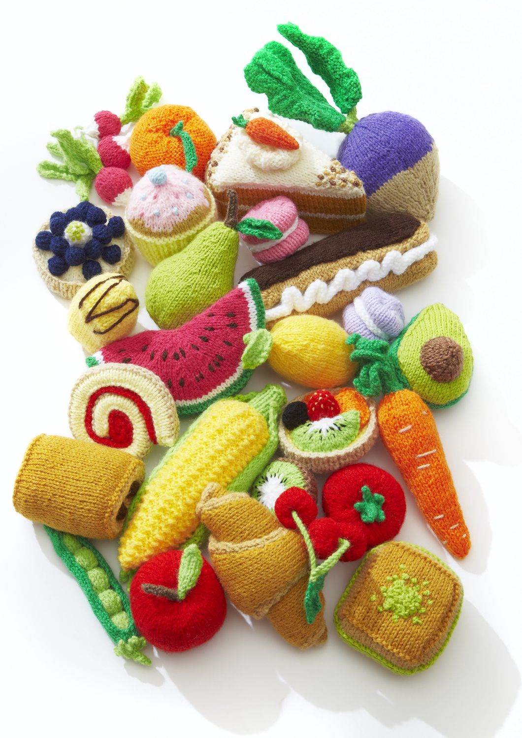 A pile of knitted foods, including fruit, vegetables, cakes and pastries.