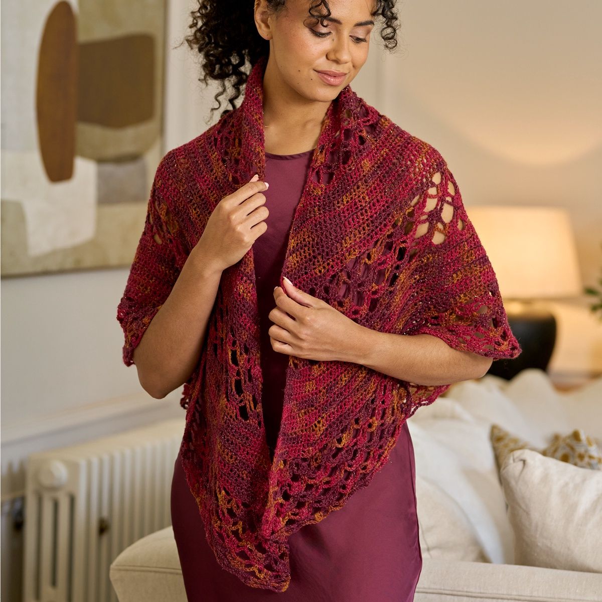 A woman is wearing a dark red crocheted shawl.