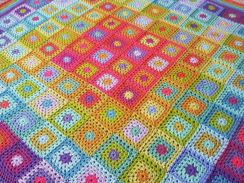 A close up of the crocheted blanket, made up of small squares in all colours of the rainbow.
