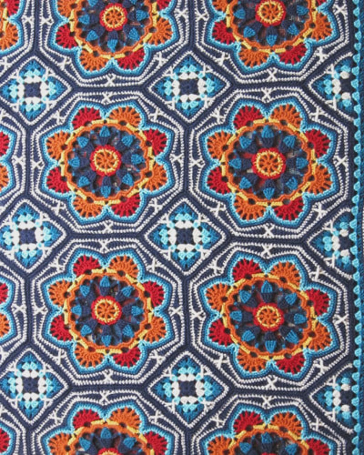 A crocheted blanket made up of octagons and squares, in various shades of blue and orange.