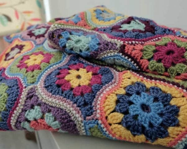 A crocheted blanket made up of lantern shaped motifs in various bright colours.