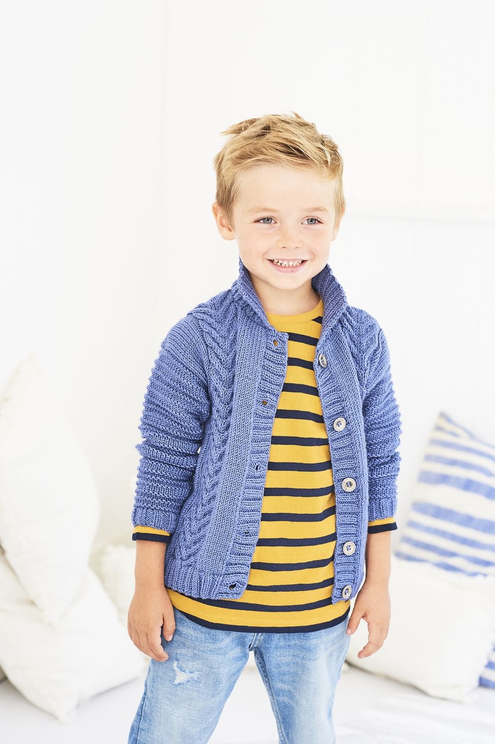 A boy is wearing a blue cable knit cardigan.