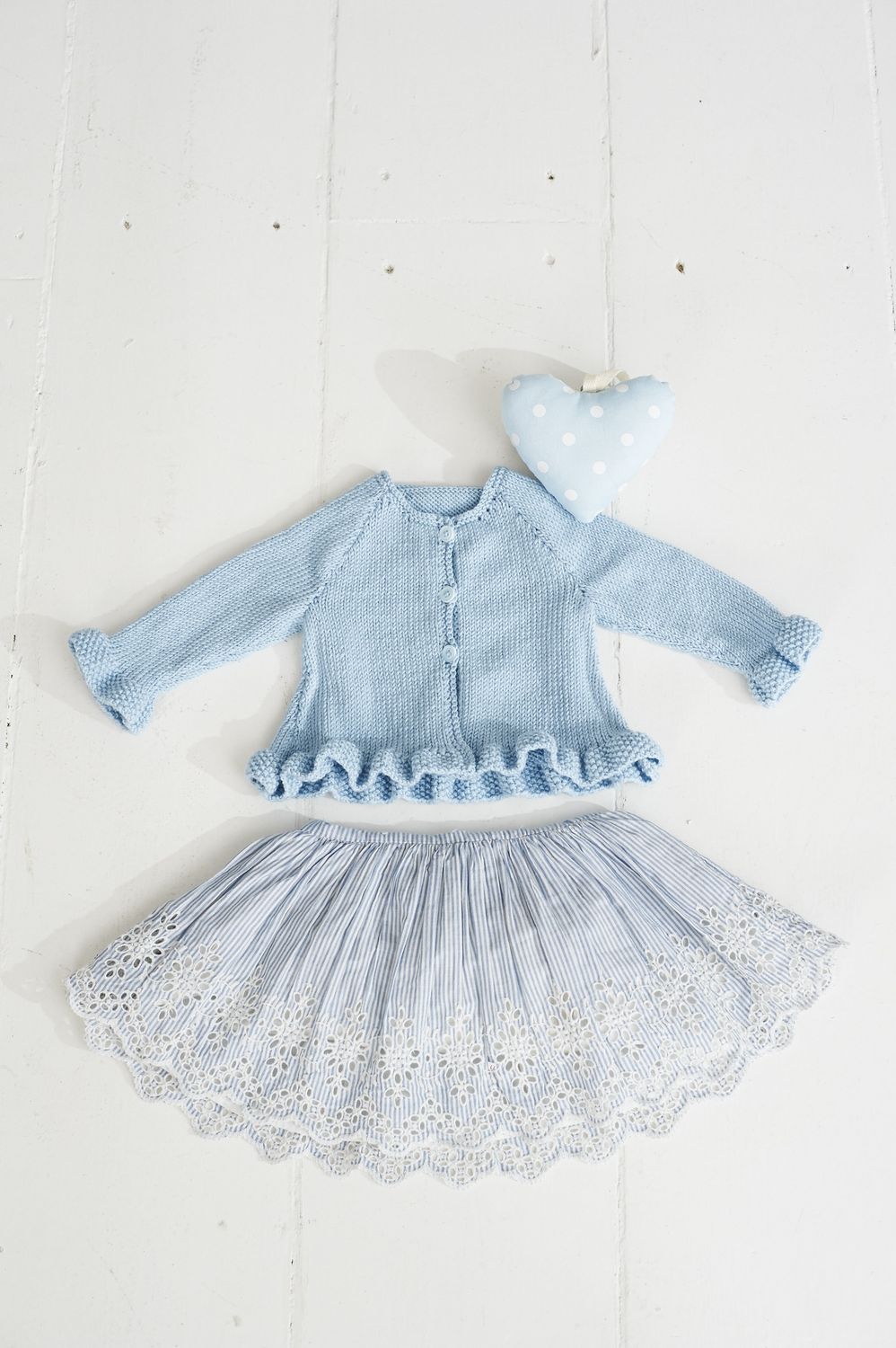 A blue knitted cardigan with frill around the the bottom edge.