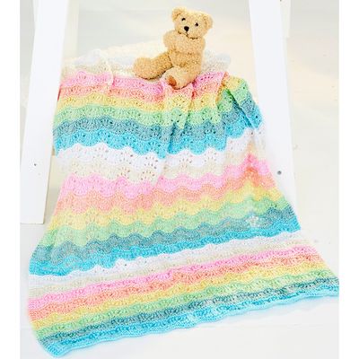A knitted ripple blanket in white, cream, pink, blue, green, yellow and orange.
