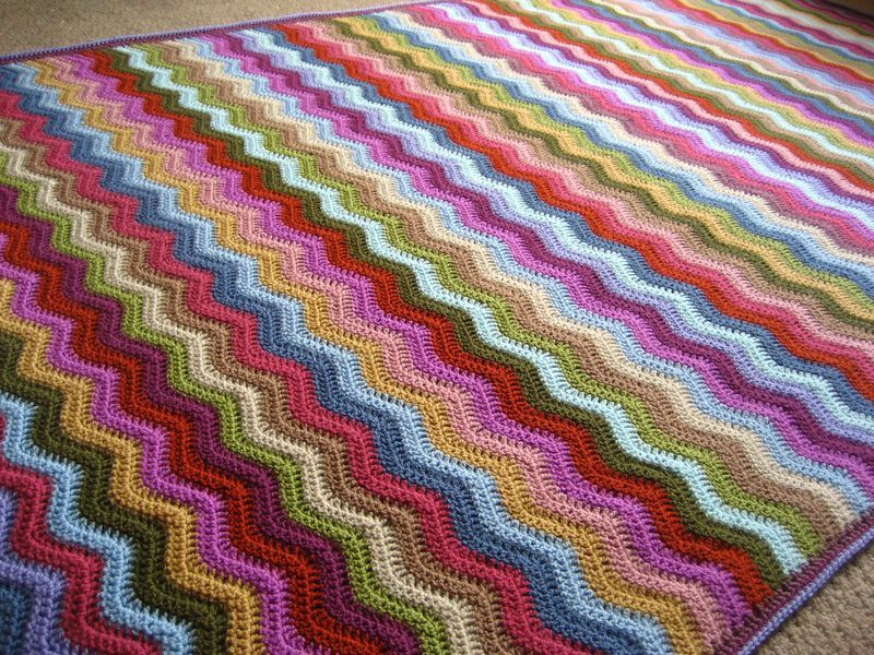 A close up of a multicoloured striped crocheted blanket. 