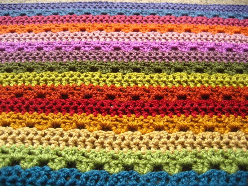 A close up of a multicoloured striped crocheted blanket.