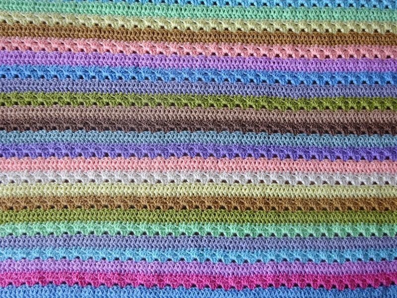A close up of a multicoloured striped crocheted blanket.